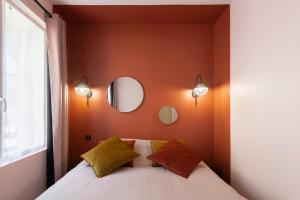 a bedroom with orange walls and a bed with two pillows at Le Cotin des Cordiers 2, F2 hypercentre, avec parking in Le Tréport