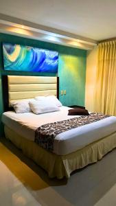a bedroom with a large bed with a painting on the wall at Hotel Aventura Suites Tucacas in Tucacas