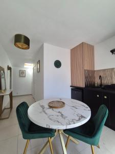 a kitchen with a table and two green chairs at La longère du Moulin in Basse-Goulaine