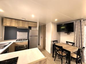 a kitchen with a table and chairs and a kitchen with a stove at Les Charmettes Mobilhome Neuf 3 ch - 2 sdb climatisé - Locsweethome in Les Mathes
