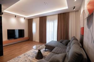 a living room with a couch and a flat screen tv at Duplex Penthouse with Jacuzzi in Sarandë