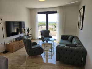 a living room with a couch and chairs and a television at Villa Green s bazenom in Medulin