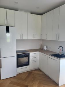 a white kitchen with white cabinets and a sink at Wake&wave in Užpelkiai