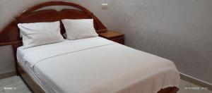 a bed with white sheets and pillows in a room at Appart Family Agadir Hay mohammadi in Agadir