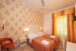 a bedroom with two beds and a red chair at Hotel Ariston Riccione in Riccione +62 photos