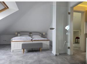 a white bedroom with a bed and a bench at Schau ins Land in Rinteln