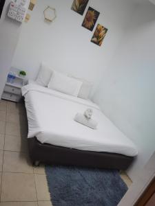 a bedroom with a white bed with a blue rug at CoMFORT GUESTS HOUSE,BUKIT BINTANG,KL in Kuala Lumpur