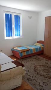 1 Schlafzimmer mit 2 Betten, einem Teppich und 2 Fenstern in der Unterkunft Apartmani Krsman 2 in Herceg-Novi