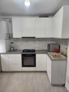 a kitchen with white cabinets and a stove and a sink at Gara De Nord 3 Rooms Apartment Superb City View in Bucharest