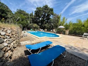 a pool with two blue chairs next to a stone wall at Gîte Citronnier Authentique et paisible in Maureillas
