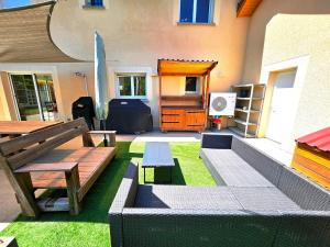 a patio with a bench and a table and a surfboard at Suréquipée avec cuisine extérieure, climatisation in Pontcharra