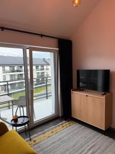 een woonkamer met een flatscreen-tv en een balkon bij Sunny Jantar in Jantar