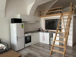 a kitchen with a ladder and a white refrigerator at Apartmán u bazénu in Šumperk
