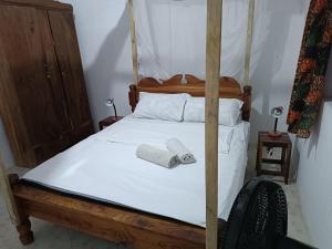 ジャンビアニにあるJambiani Holiday Houseの四柱式ベッドとタオル2枚を備えた寝室