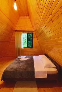 Una cama en una habitación de madera con ventana. en Panorama cottage Martvili, en Martvili