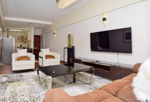 a living room with a couch and a tv on a wall at Davinia Haven in Nairobi