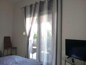 a bedroom with a bed and a window with curtains at Elina House in Nikiti