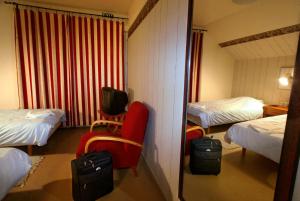 a hotel room with two beds and a red chair at Villa Huvila in Savonlinna