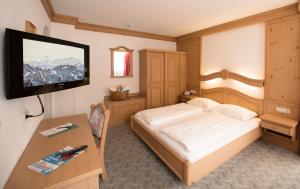 a bedroom with a bed and a desk with a television at Hotel zum grünen Tor in Tux