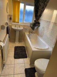 a bathroom with a tub and a toilet and a sink at Bright Double Room near NewCross Hospital in Fallings Park