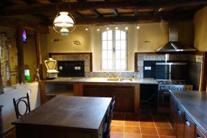 une grande cuisine avec une table et une cuisinière dans l'établissement Auberg'IN Gîte, à Mirandol-Bourgnounac