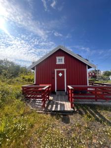 a red barn with two benches in front of it at Charming cabin in Henningsvær in Henningsvær +11 photos