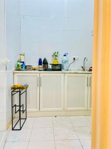 cocina con armarios blancos y suelo de baldosa blanca en Furnished Room at Ghayathi, en Ghayathi