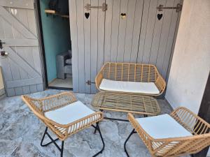 Tres sillas de mimbre y un banco en un porche. en Sea Nest, en Pafos