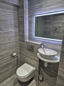 Un baño con lavabo, inodoro y espejo. en Sea Nest, en Pafos