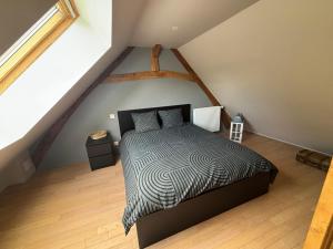 a bedroom with a black and white bed in a attic at Le magnolia in Épieds