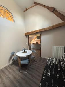 a room with a bed and a table and chairs at Le magnolia in Épieds