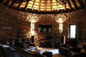 - un salon avec des fauteuils en cuir et un mur en pierre dans l'établissement Natures View, à Pretoria