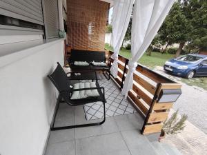 a balcony with two chairs and a table and a car at Apartman Jež 4 De Lux - self check in, free parking in Karlovac