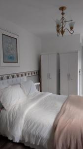 ein Schlafzimmer mit einem weißen Bett und einem Kronleuchter in der Unterkunft Chalé Luxuoso de Hospedes in Teresópolis