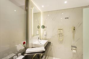 un bagno bianco con lavandino e specchio di Calypso Palace a Faliraki