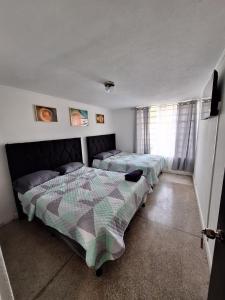 a bedroom with two beds and a window at Hotel Aurora in Guatemala