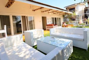eine Terrasse mit weißen Möbeln und einem Tisch in der Unterkunft Villa Nazuri w Caretaker in Candolim