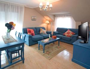 a living room with blue couches and a tv at Apartamentos Costa Noja in Noja