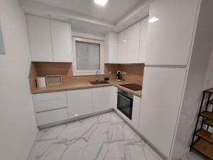 a kitchen with white cabinets and a sink and a window at Vikendica Dijana Ramsko jezero in Ploča