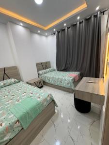 a bedroom with two beds and a table in it at La Prestigia chalet in Hurghada