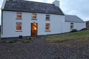 a white house with a cat sitting in front of it at Derriana Cottage in Waterville