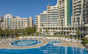 a large pool with white chairs and buildings at Sunset Resort Apartament C3 - 22 in Pomorie