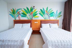 two beds in a room with plants on the wall at UFJ HOTEL Sầm Sơn in Sầm Sơn +56 photos