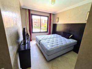 a bedroom with a bed and a television and a window at Palm river marrackech in Marrakesh