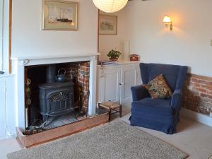 un salon avec une cheminée et une chaise bleue dans l'établissement Bow Cottage, à Fordwich