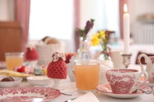 a table with plates and cups and a glass of orange juice at Gästehaus Rieper in Jork