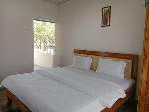 une chambre avec un lit avec des draps blancs et une fenêtre dans l'établissement Nvalai Villa with Swimming pool, à Panchgani