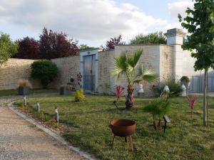 a garden with palm trees and a building at L'Enclos de La Grande Flûte in Douzat