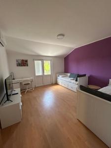 a bedroom with purple walls and a bed and a desk at Apartment Kix in Rab