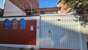un garage con cancello bianco e muro di mattoni di Los Profesionales Casa Independiente a Cuzco